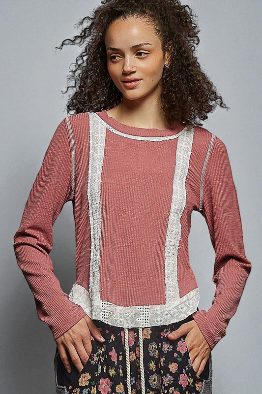 Woman wearing a pink sweater with lace details on a gray background