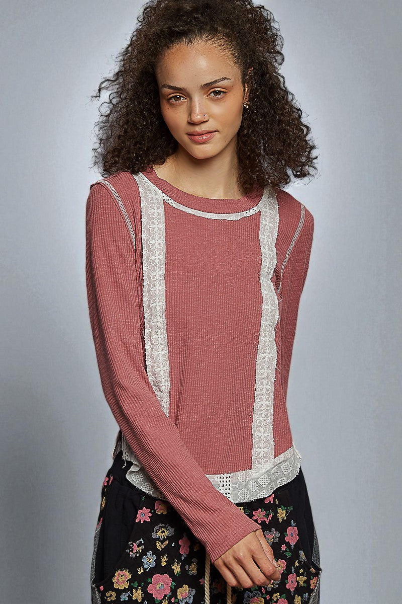 Woman wearing a pink sweater with lace details on a gray background