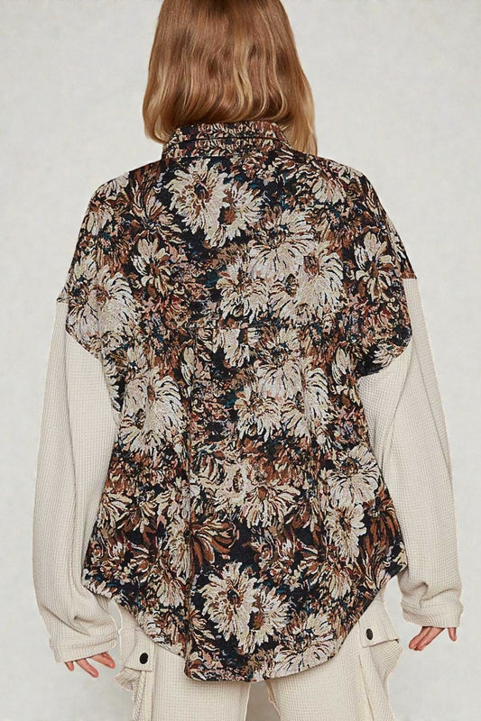 Person wearing a floral patterned vest over a beige sweater on a white background