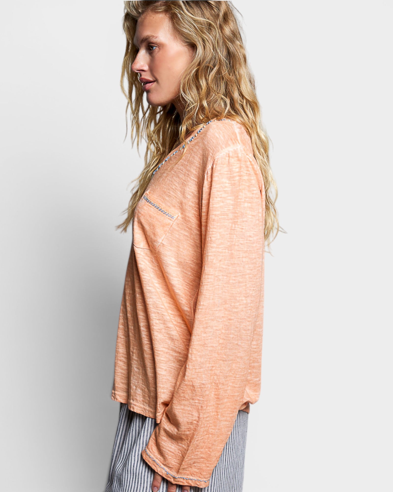 Woman wearing a peach-colored sweater against a plain background