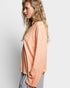 Woman wearing a peach-colored sweater against a plain background