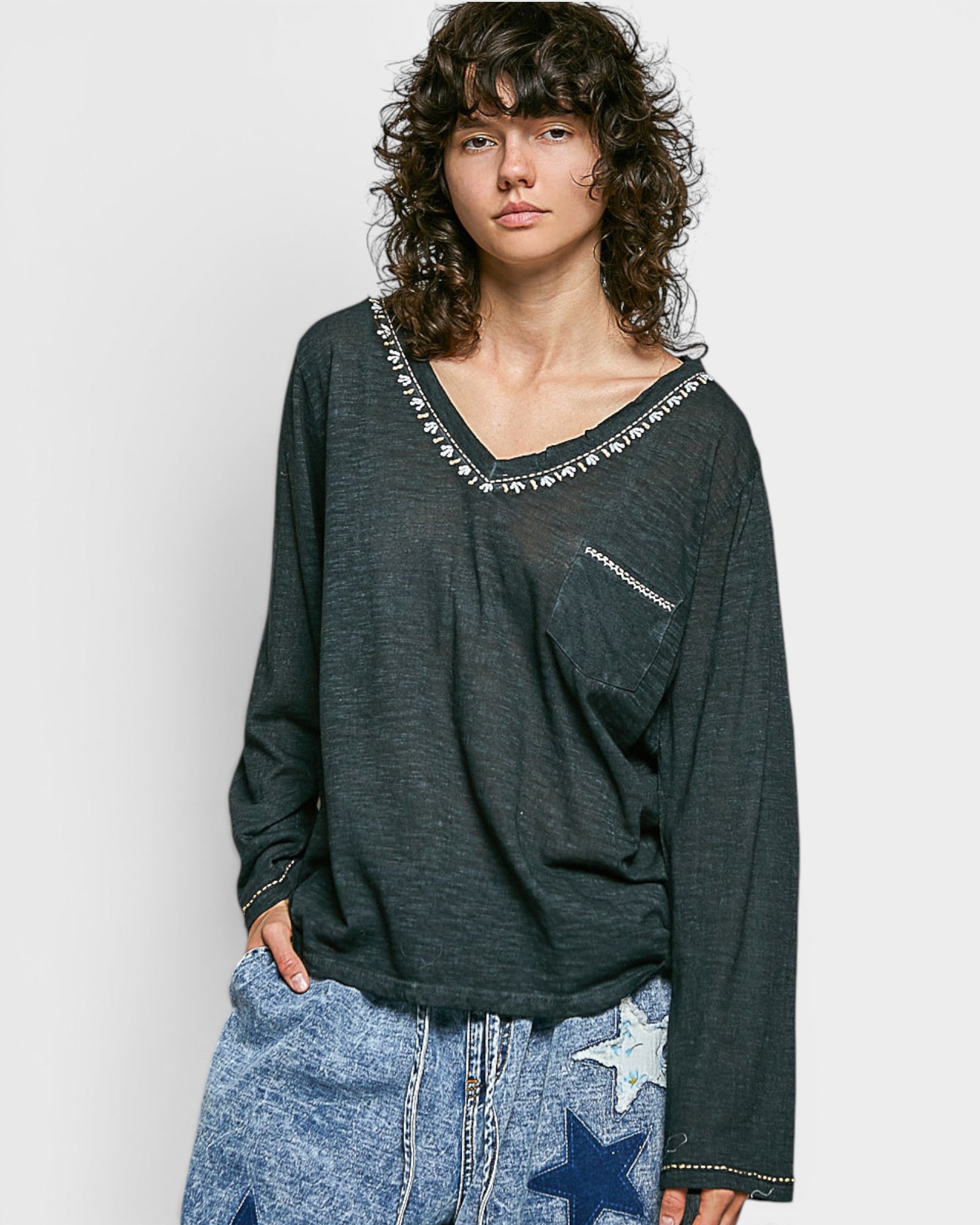 Person wearing a black long-sleeve top with star patterns on a plain background
