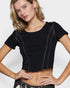 Woman wearing a black crop top against a plain background