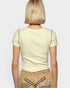 Person wearing a light-colored t-shirt and patterned skirt on a plain background