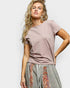 Woman wearing a mauve t-shirt and patterned skirt on a white background