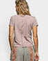 Person wearing a mauve t-shirt with a floral pattern on the bottom half of the pants against a white background