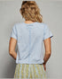 Person wearing a light blue top with a plain background