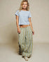 Woman wearing a light blue crop top and patterned pants on a beige background