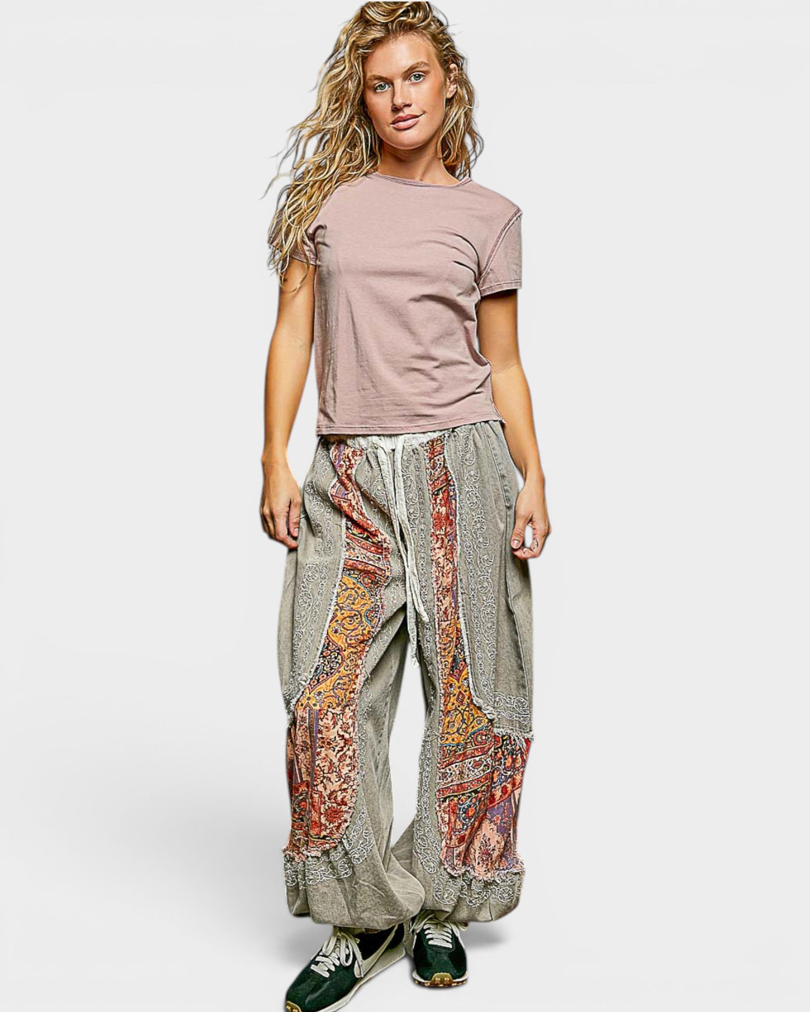 Woman wearing a pink top and patterned pants on a white background