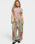 Woman wearing a pink top and patterned pants on a white background