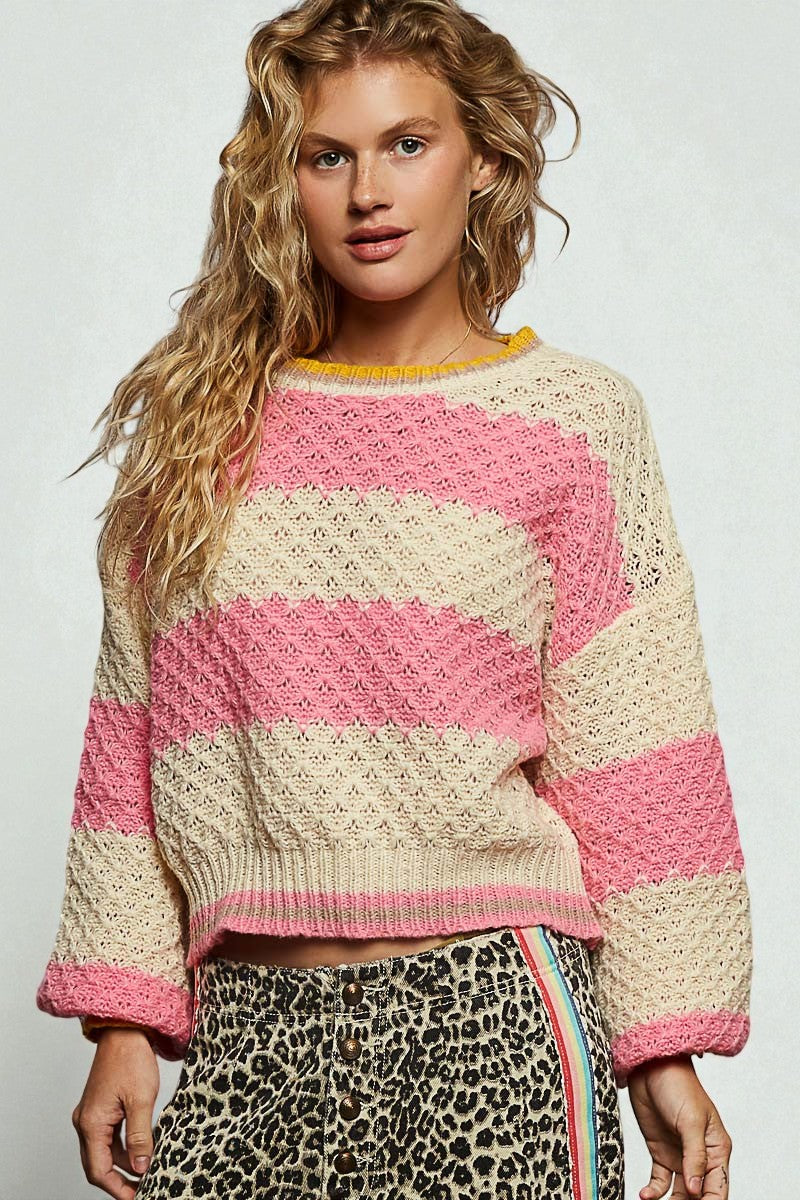 Woman wearing a pink and beige striped sweater with a plain background