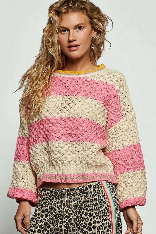 Woman wearing a pink and beige striped sweater with a plain background