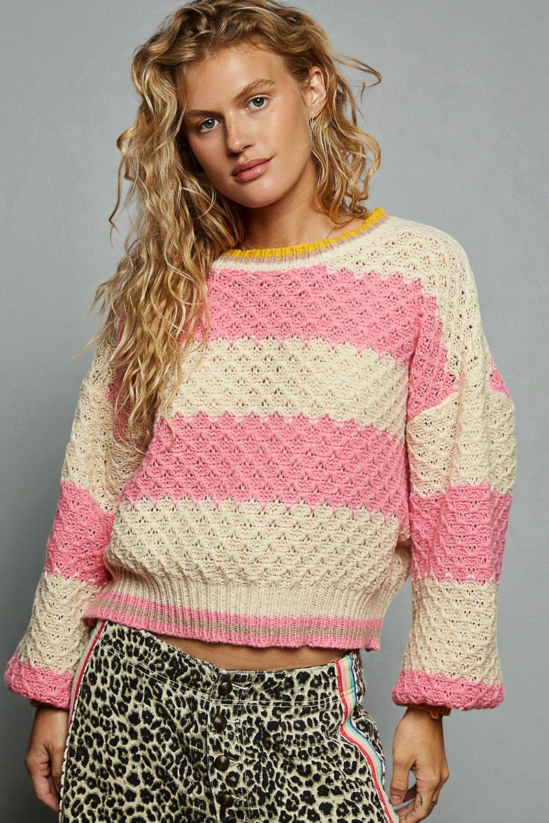 Woman wearing a pink and beige striped sweater with leopard print pants on a gray background
