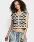 Woman wearing a black and white patterned sleeveless top with denim shorts on a white background