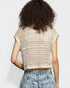 Person wearing a beige crochet top and denim shorts on a light gray background