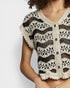Woman wearing a black and white crochet cardigan on a light gray background