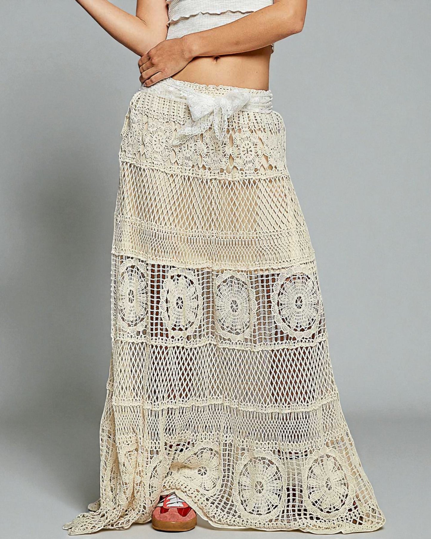 Beige crochet skirt worn by a person on a gray background