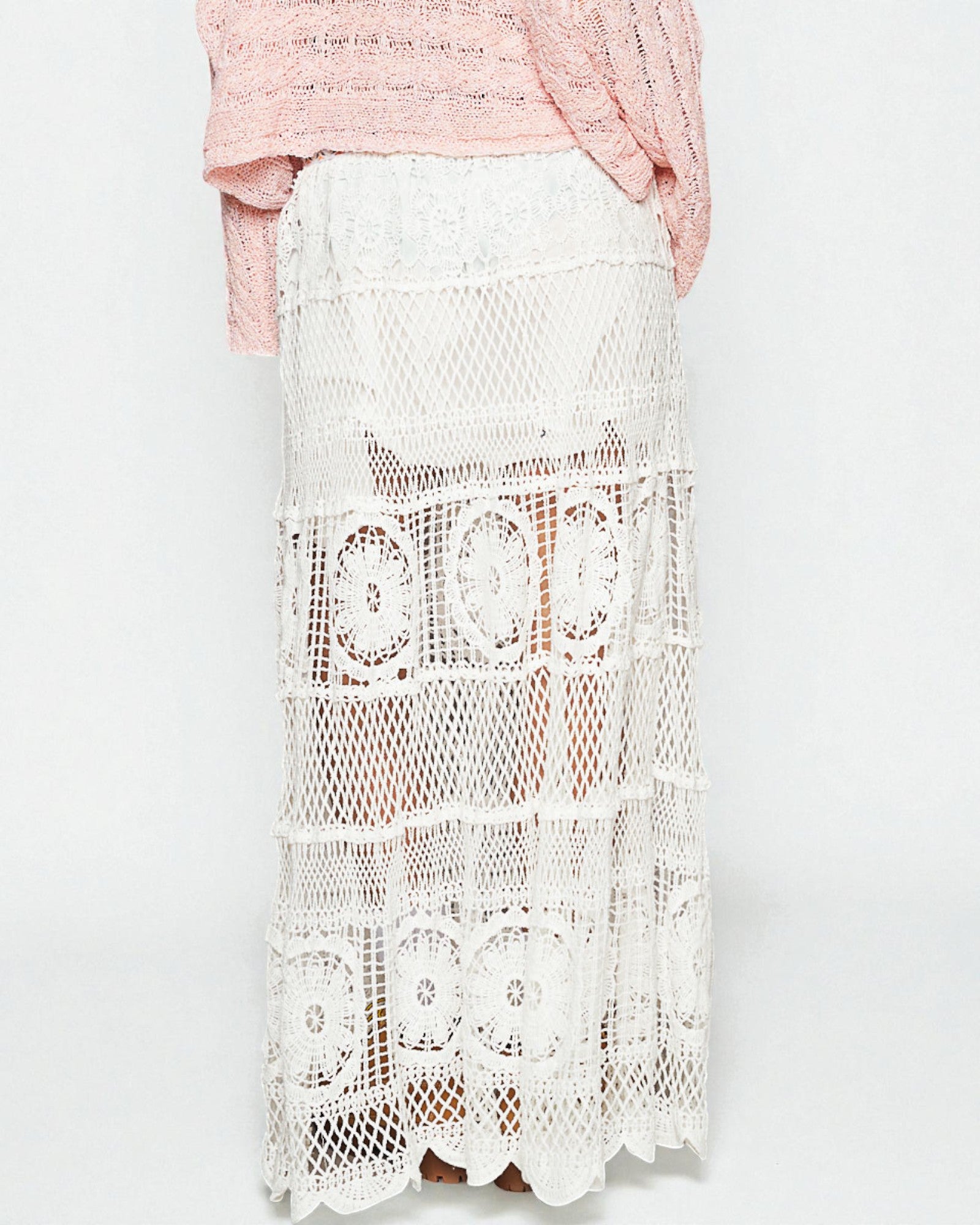 White lace skirt worn by a person on a light gray background