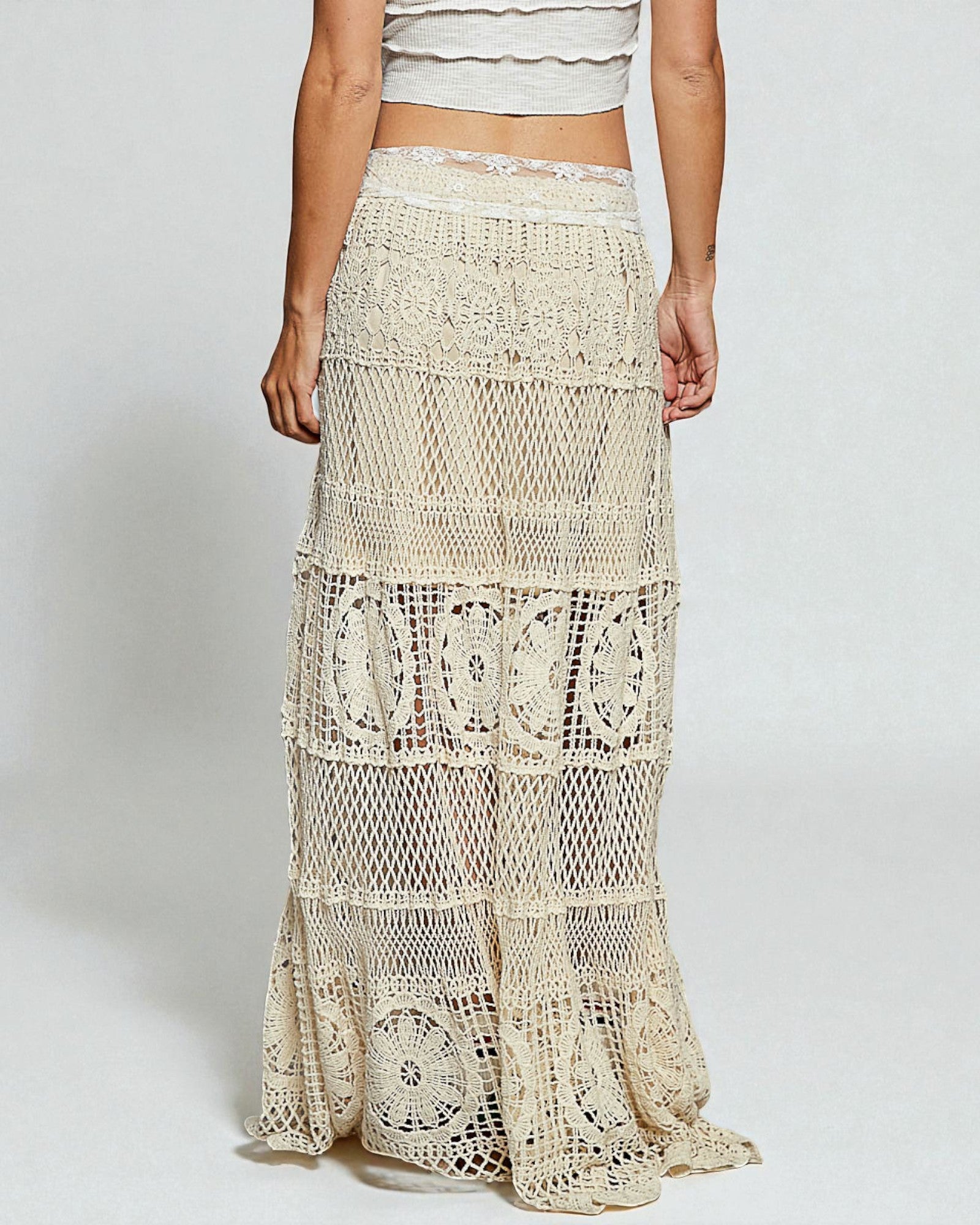 Beige lace skirt worn by a person on a plain background
