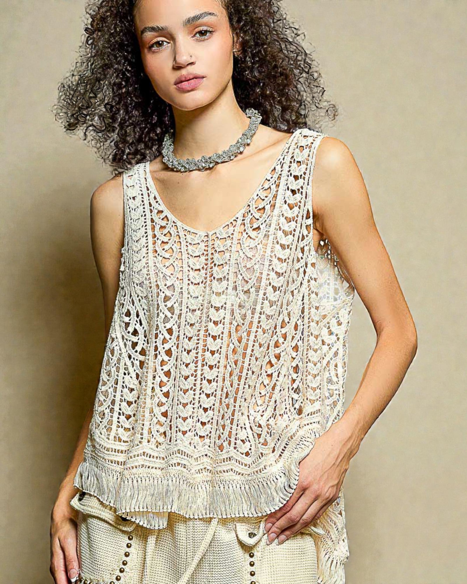 Woman wearing a beige crochet top against a beige background