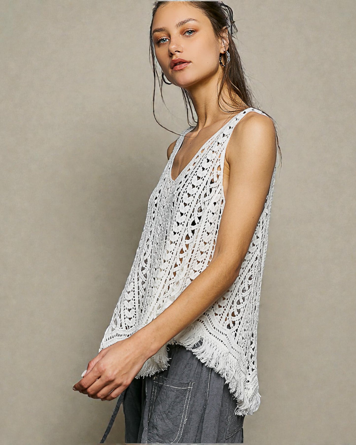 Woman wearing a white crochet tank top against a beige background