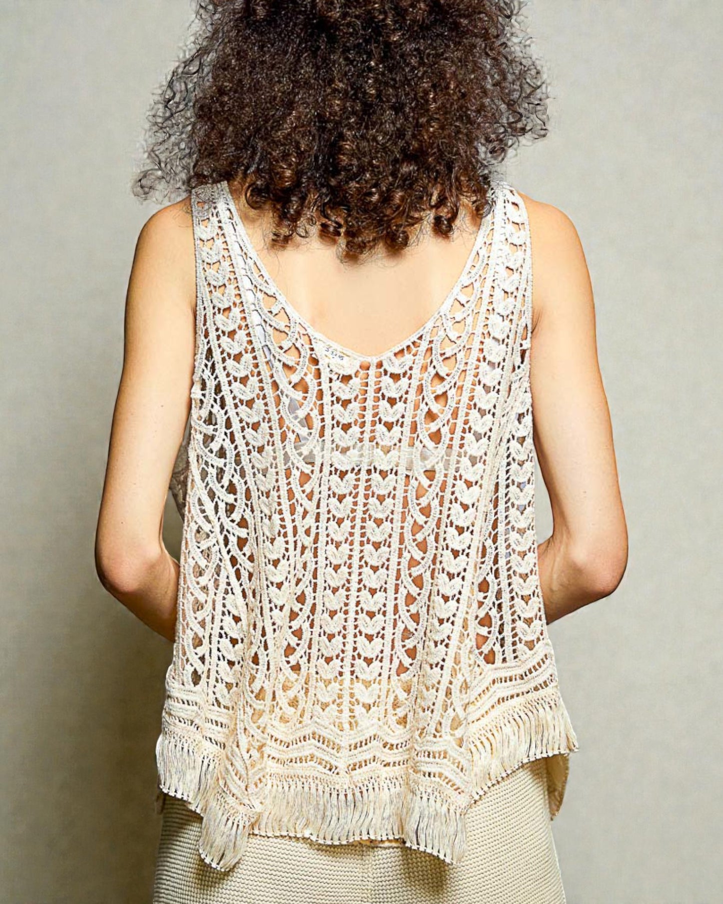 Person wearing a white lace tank top against a neutral background