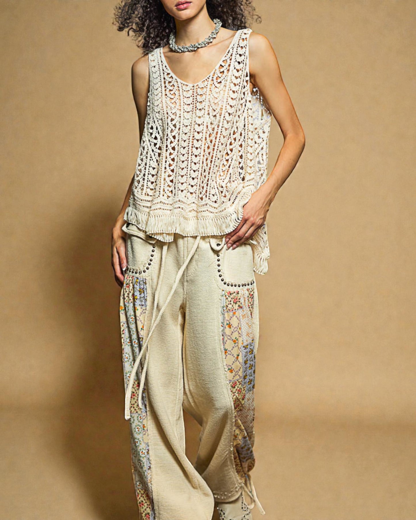 Woman wearing a crochet top and patterned pants against a beige background