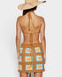 Woman wearing a brown crochet dress with colorful patterns and a wide-brimmed hat on a white background