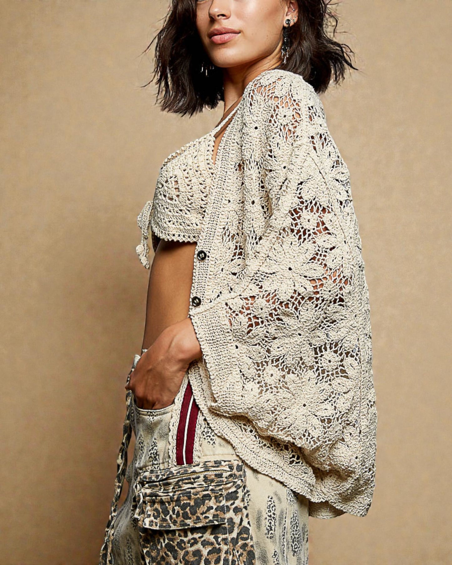 Woman wearing a beige lace top against a beige background