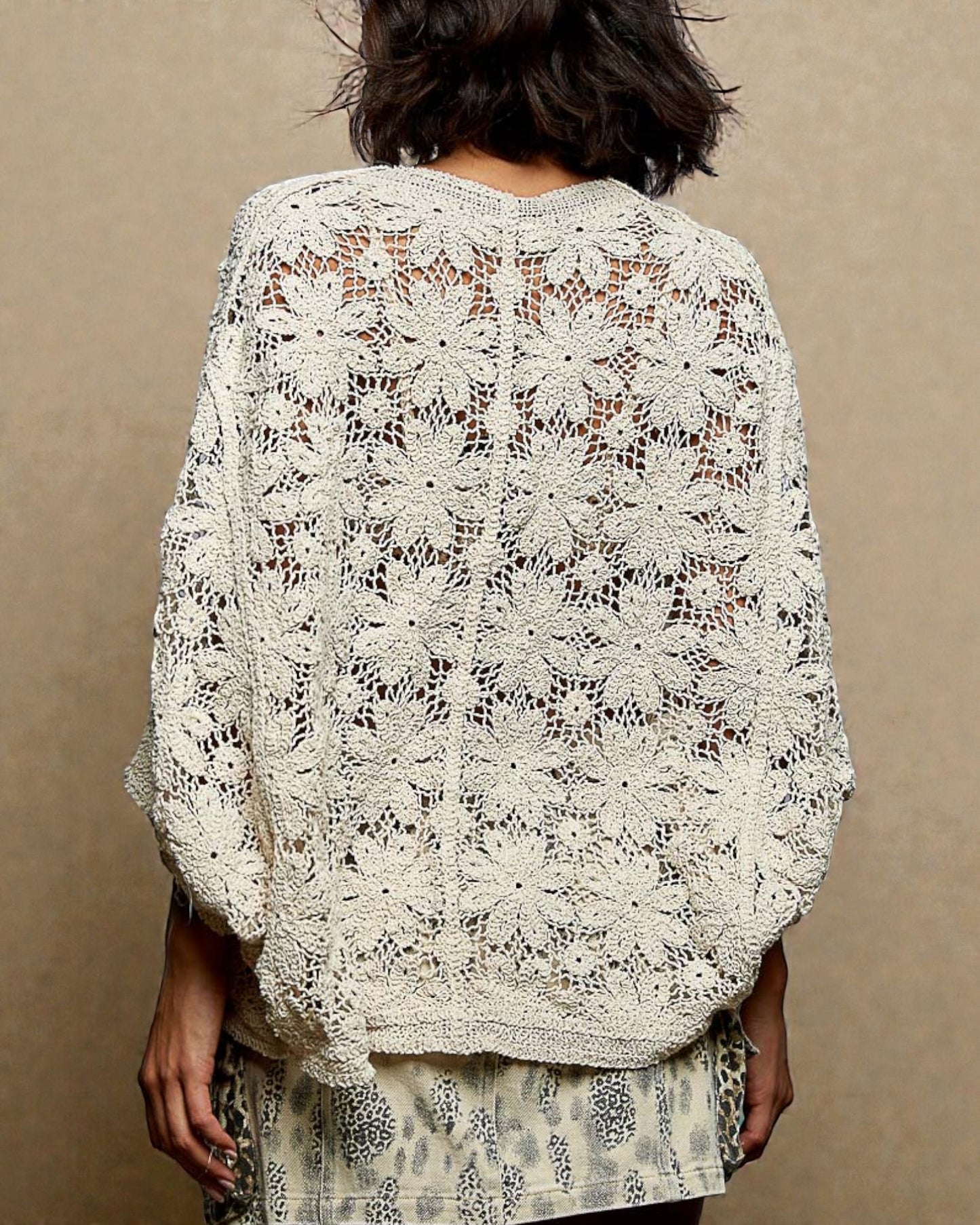 Person wearing a white lace shawl against a beige background