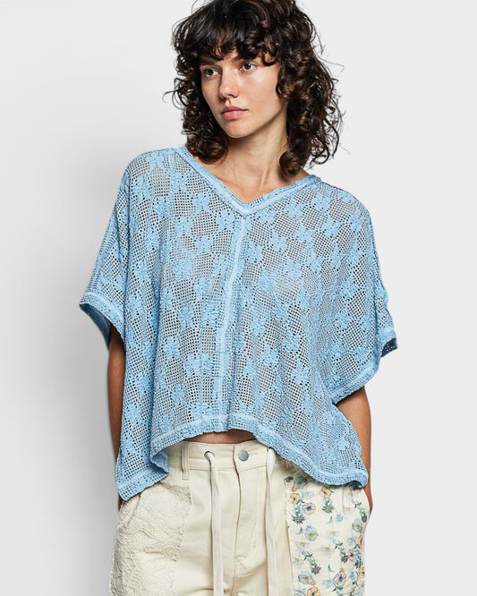 Woman wearing a blue crochet top against a white background
