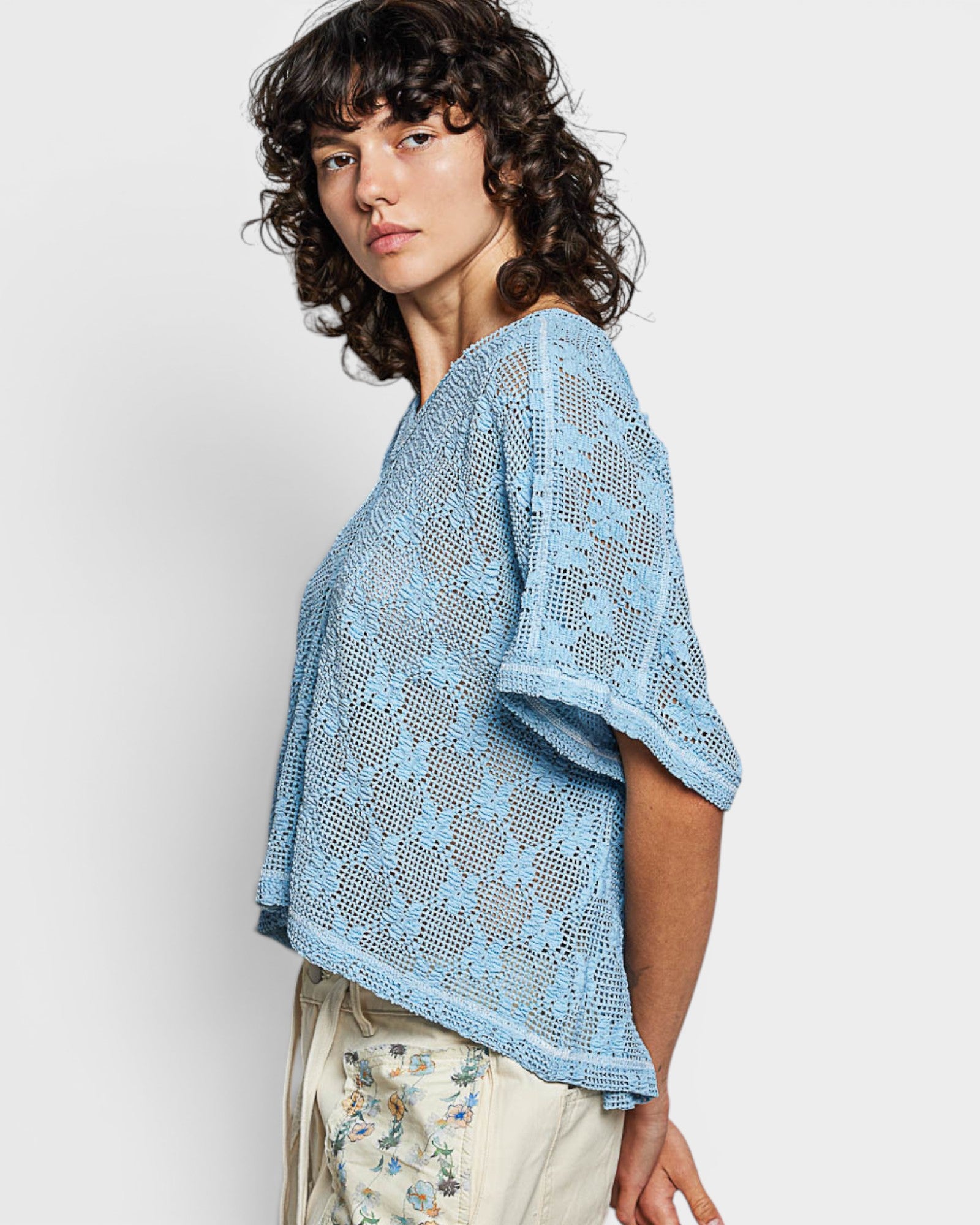 Woman wearing a light blue lace top against a white background