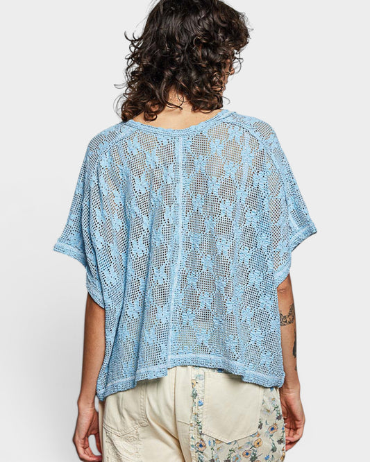 Person wearing a light blue crochet top on a white background