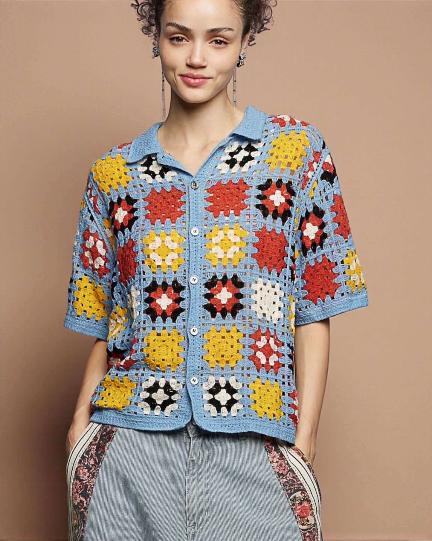 Woman wearing a colorful crochet jacket against a brown background