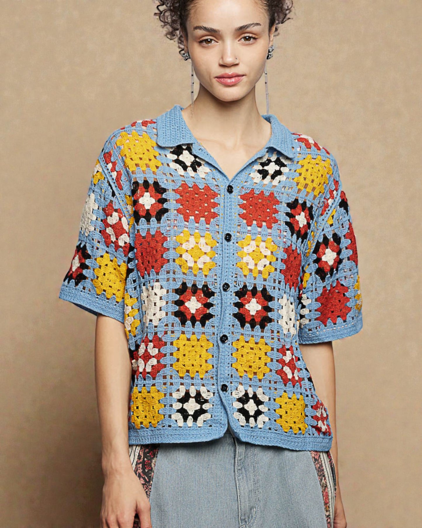 Woman wearing a colorful crochet shirt against a beige background