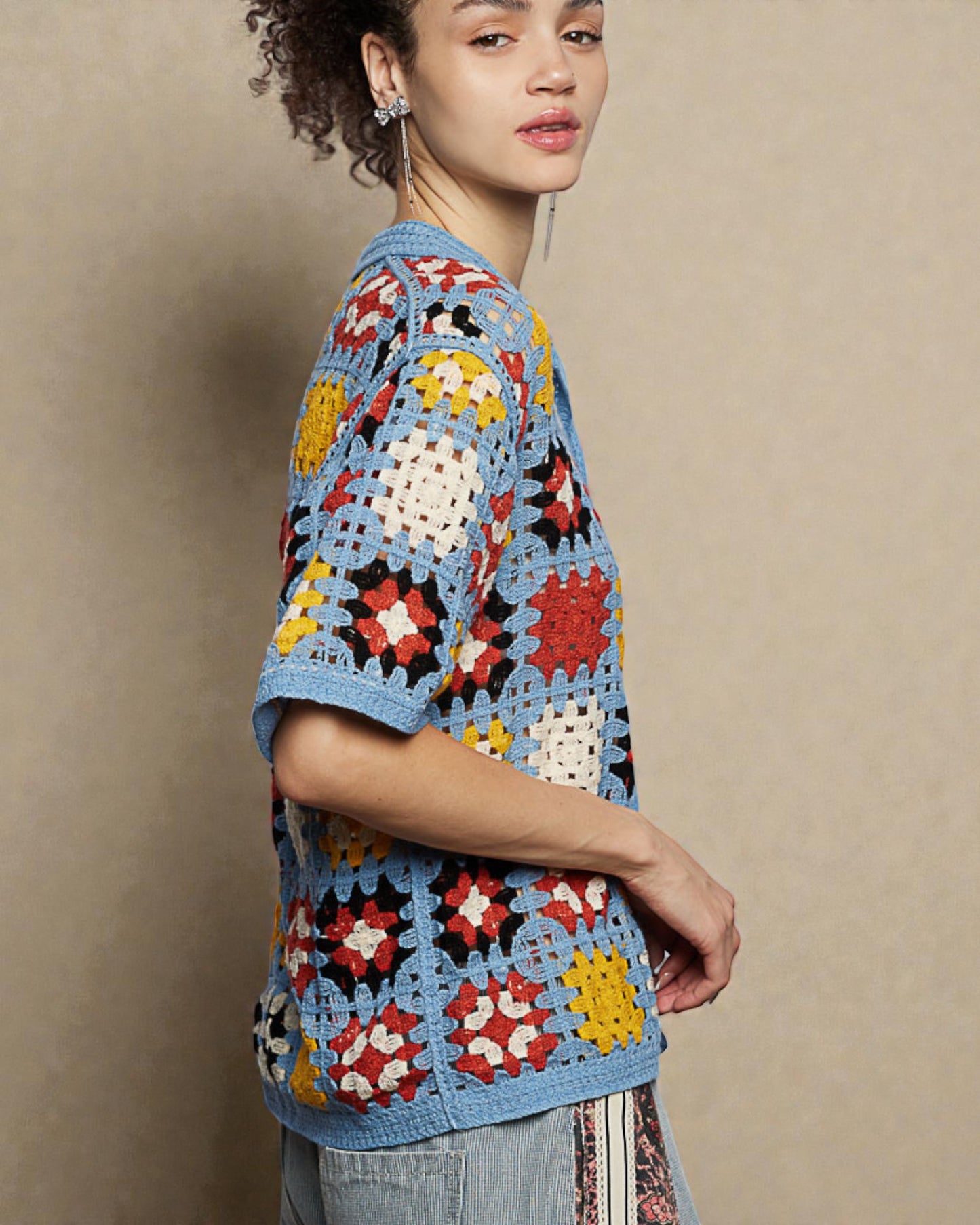Woman wearing a colorful crochet sweater against a beige background