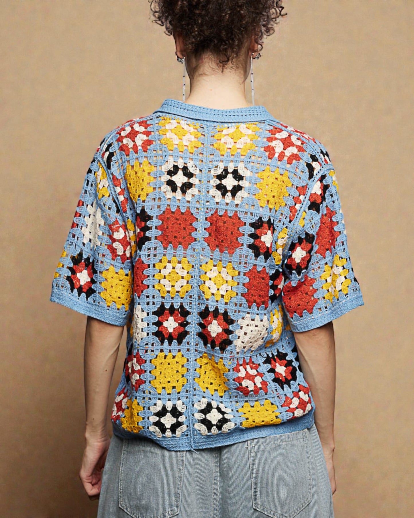Person wearing a colorful crochet top against a beige background