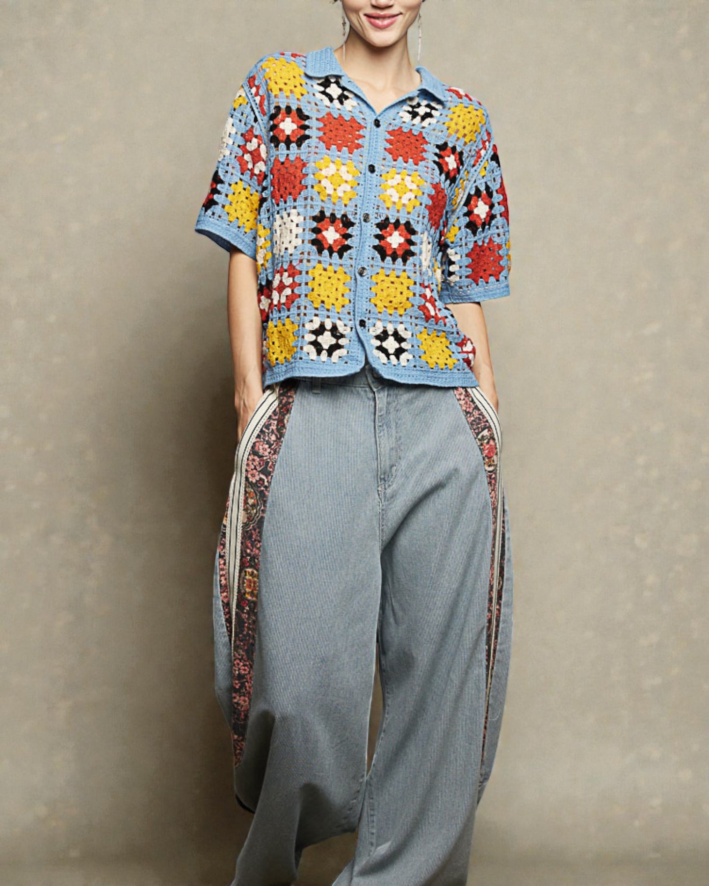 Person wearing a colorful crochet top and light blue jeans against a neutral background