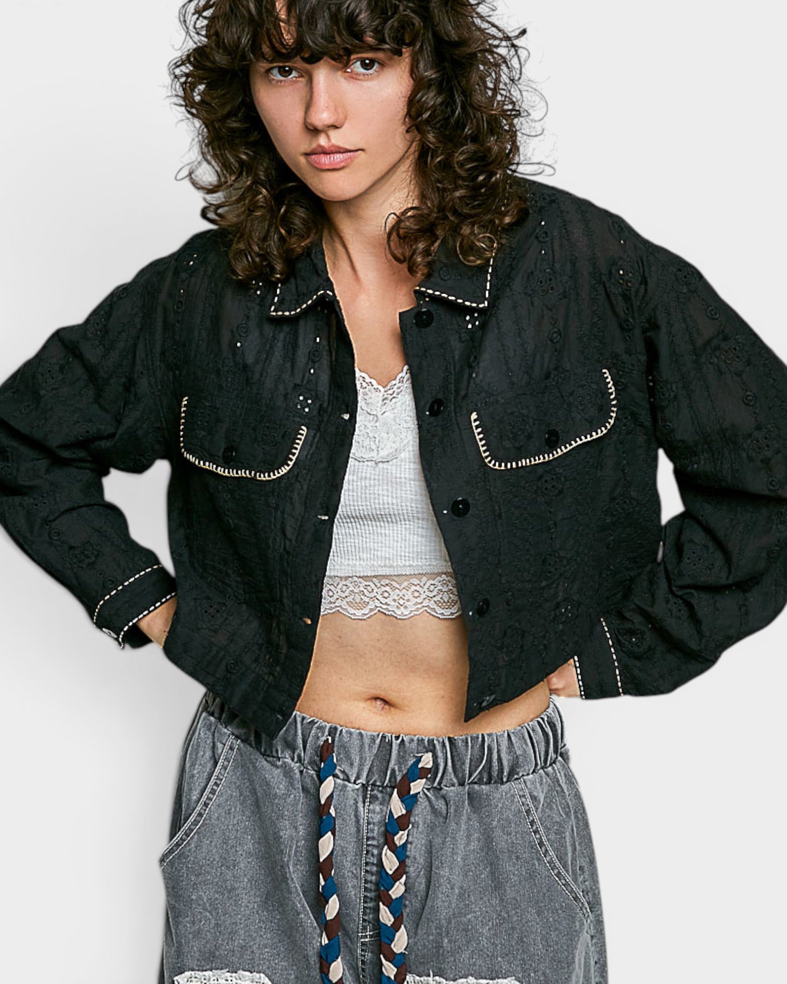 Person wearing a black denim jacket with white trim on a plain background
