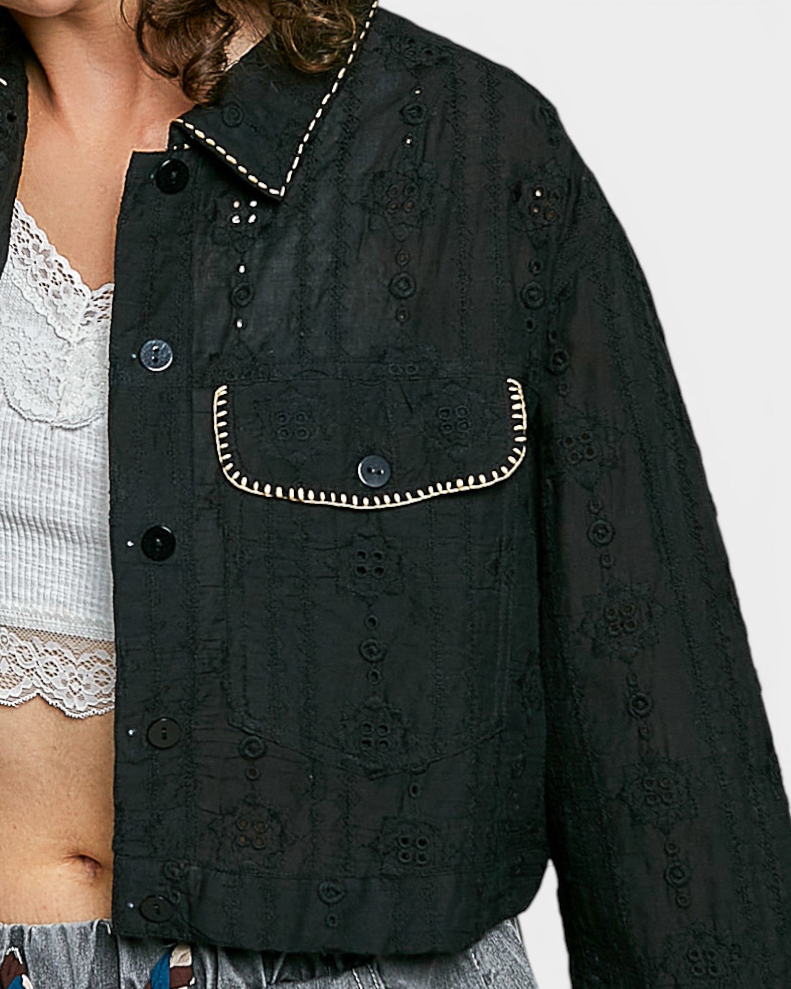 Black embroidered jacket with white trim on a plain background