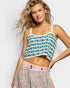 Woman wearing a patterned top and skirt against a plain background