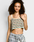 Woman wearing a patterned tank top and plaid pants against a plain background