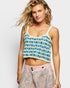 Woman wearing a patterned crop top and pink pants on a white background