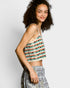 Woman wearing a patterned crop top and plaid pants on a plain background