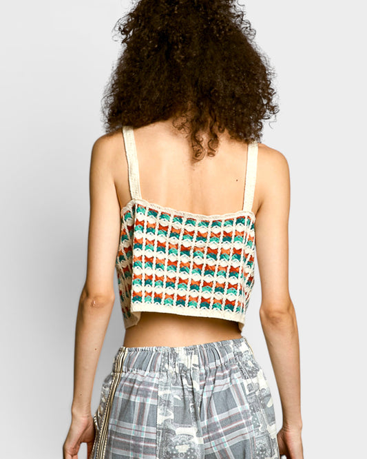 Person wearing a patterned top and plaid pants on a plain background
