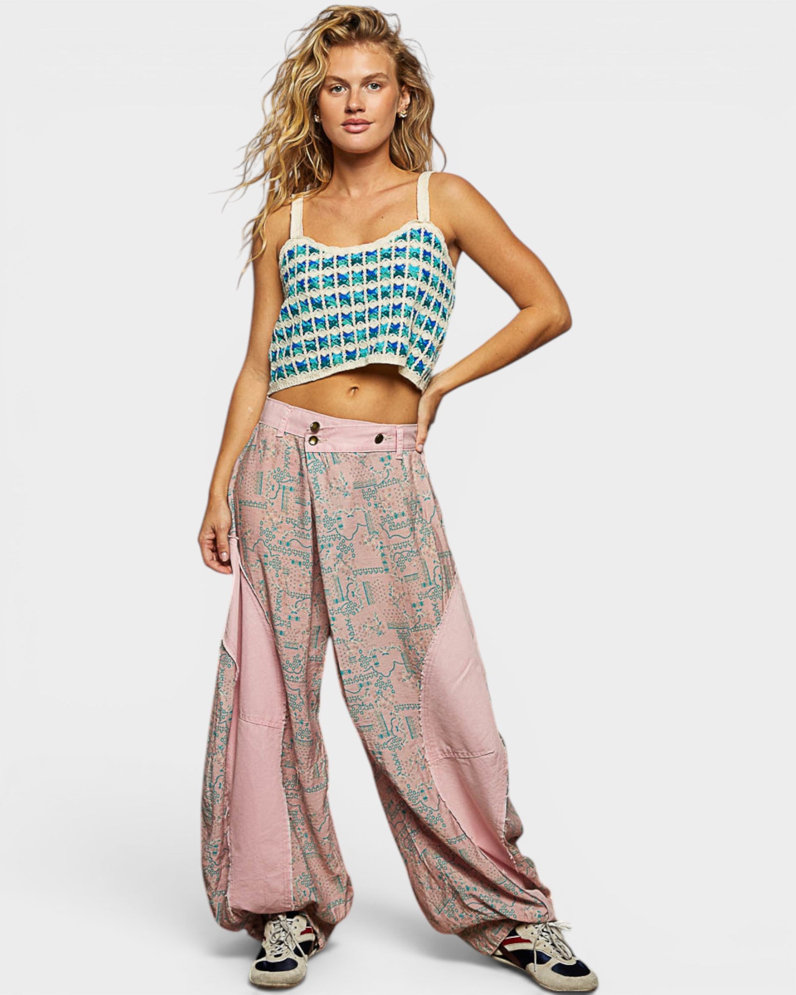 Woman wearing a patterned top and pink pants on a white background