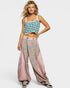 Woman wearing a patterned top and pink pants on a white background