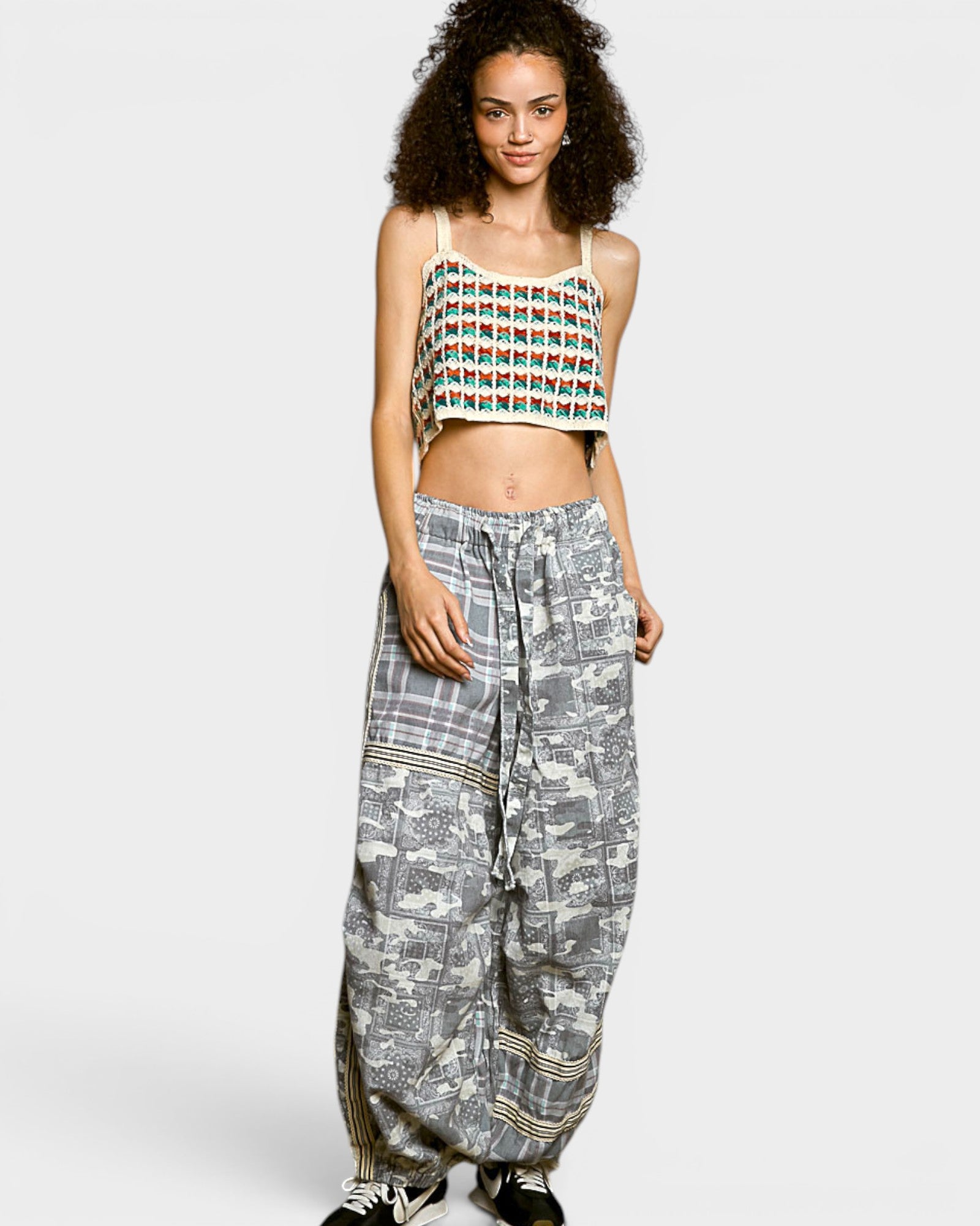 Woman wearing a patterned top and wide-leg pants on a white background