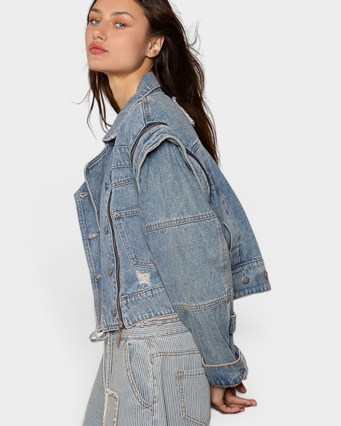 Woman wearing a light blue denim jacket on a white background