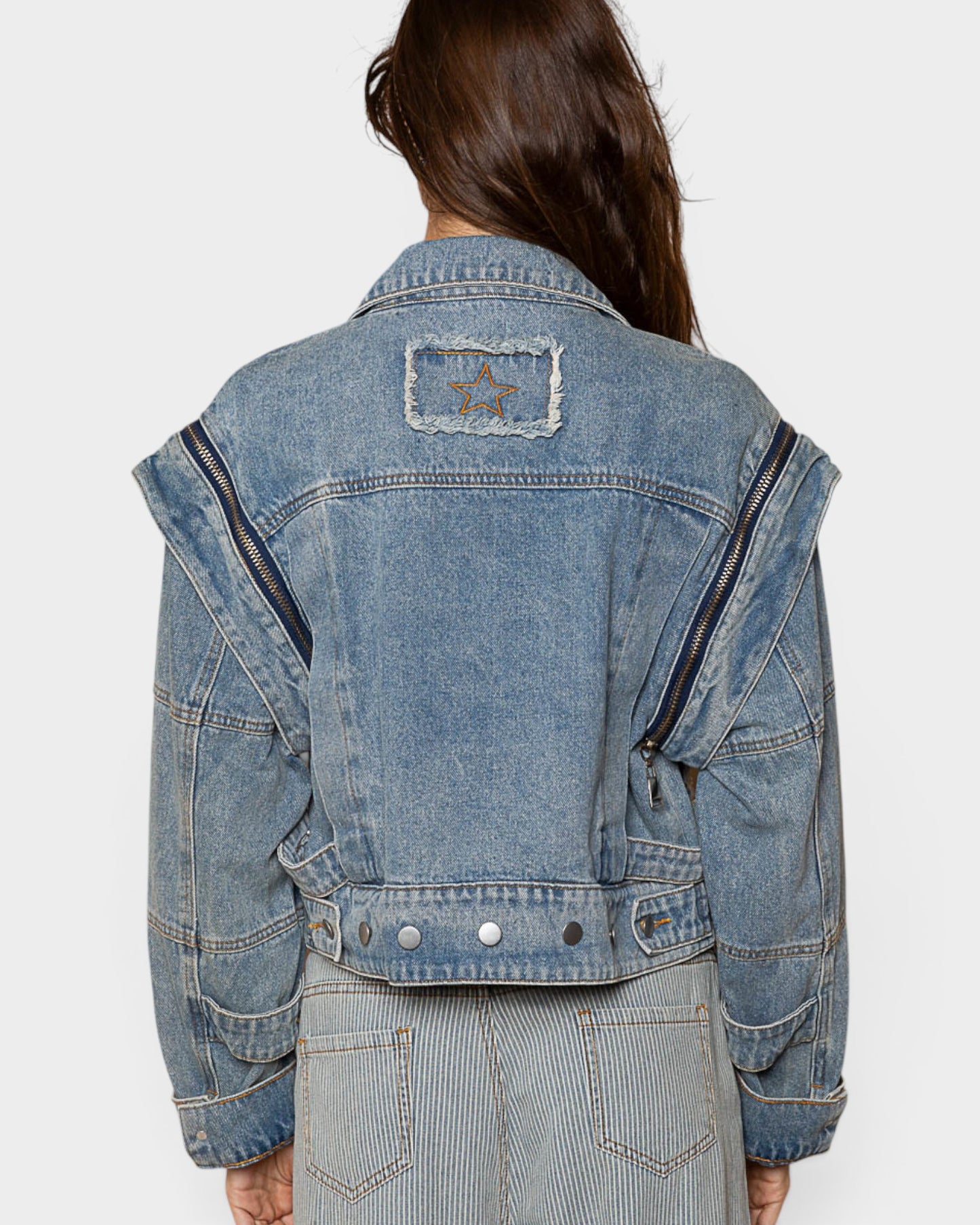 Blue denim jacket with star patch on a white background